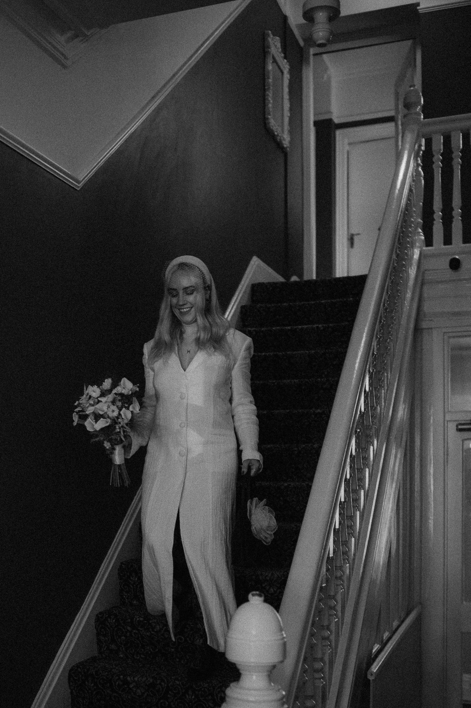 Figure in white attire walking down a dimly lit staircase creating an eerie atmosphere.