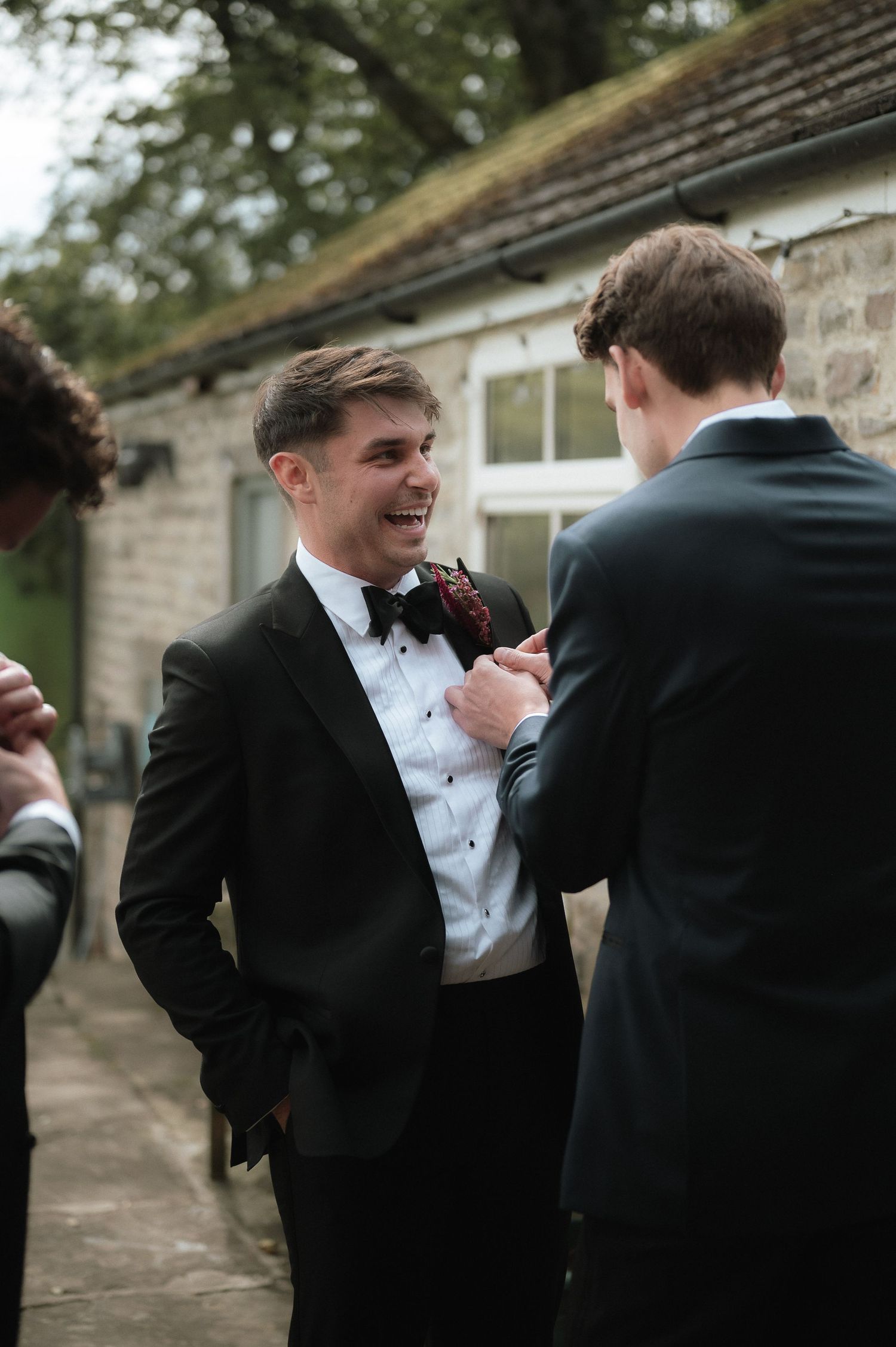 Formal wedding party moment with men in black tuxedos and bow ties.