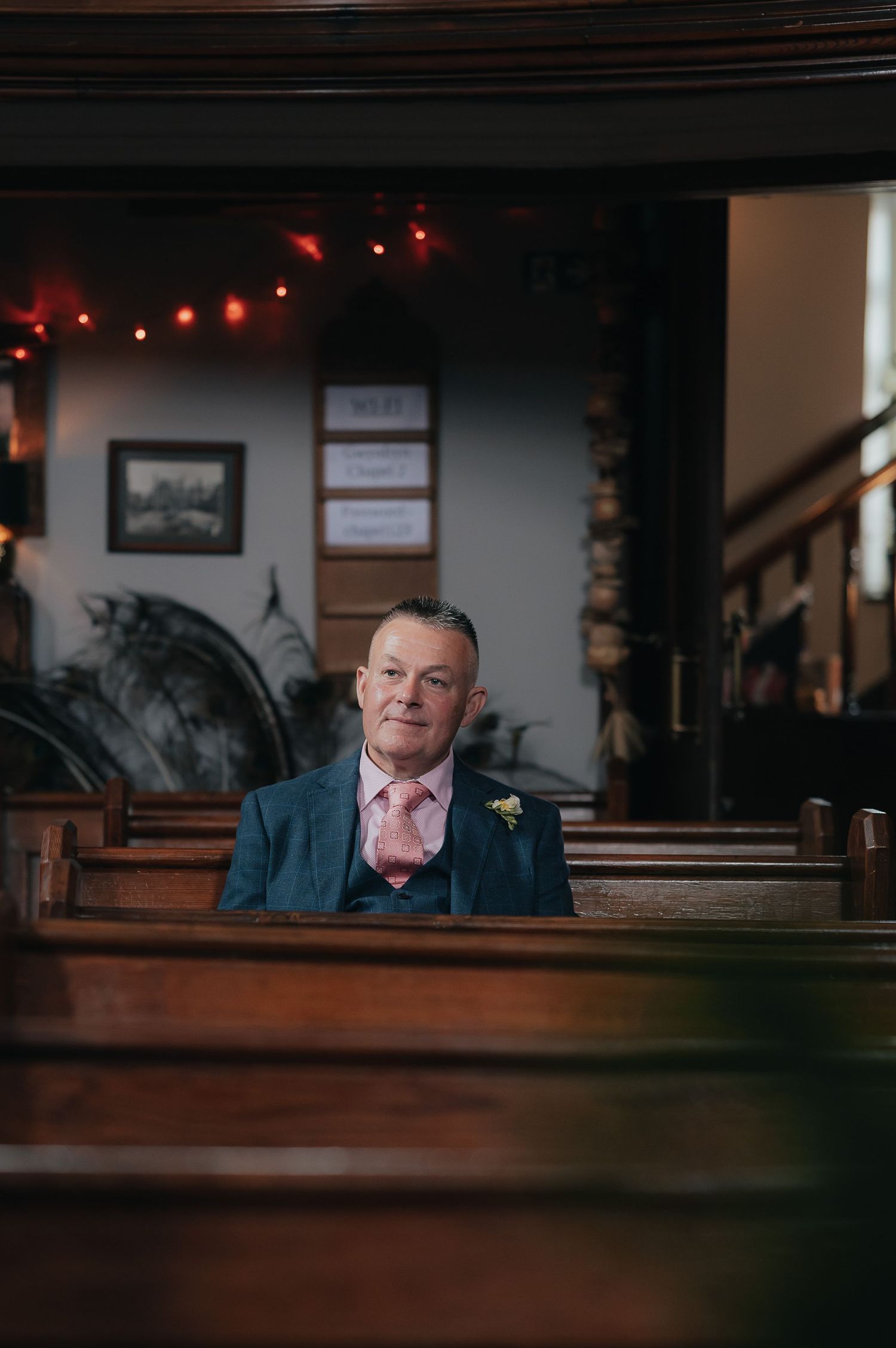 Person sitting alone in church pew wearing a teal suit jacket.