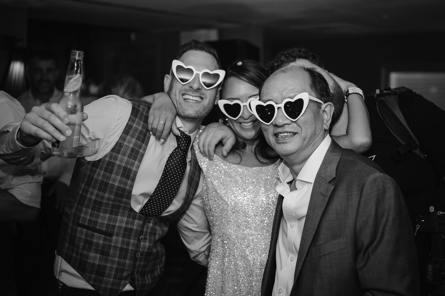 Party guests wearing retro sunglasses pose playfully at a celebration.