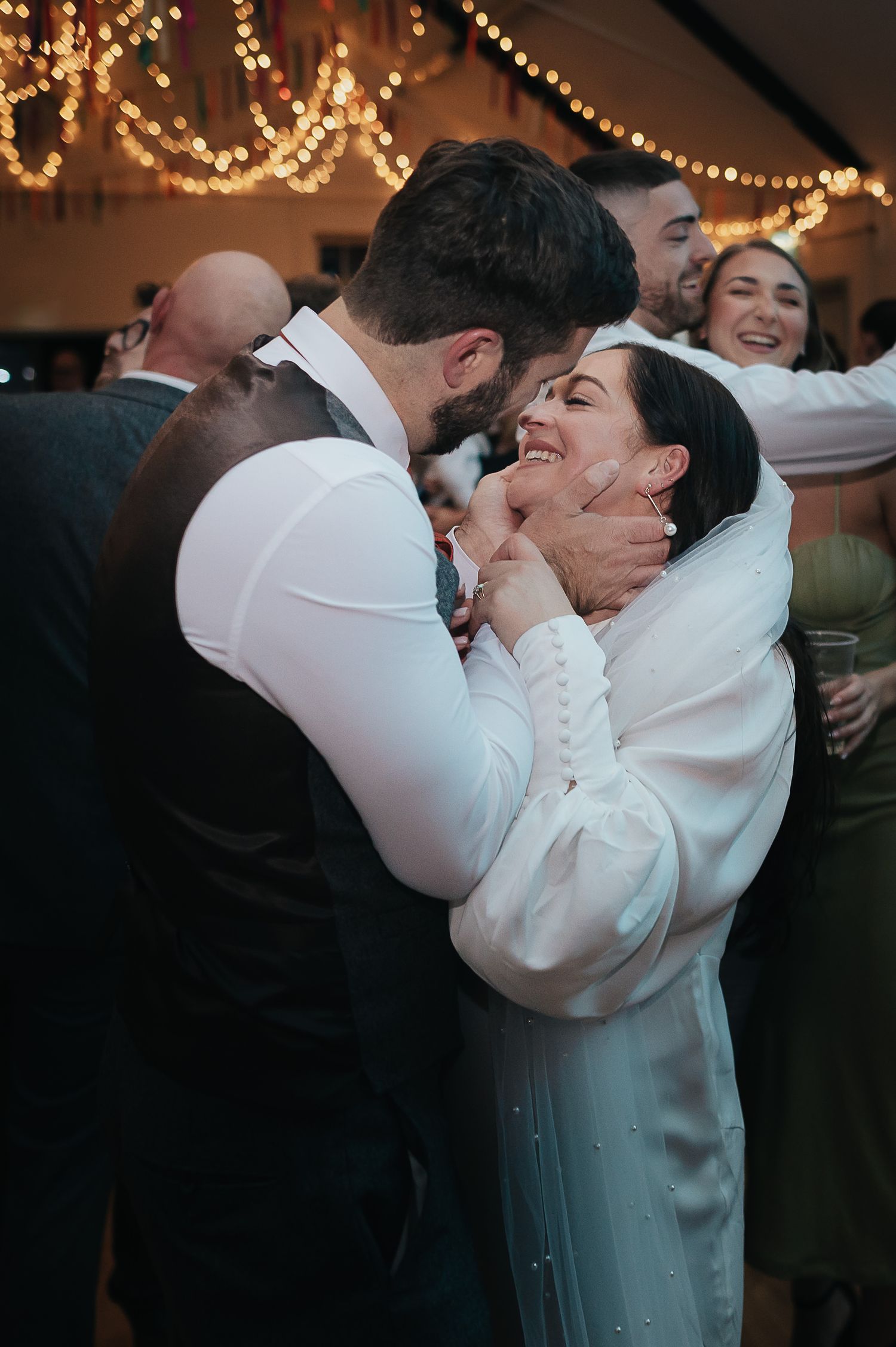A newlywed couple shares an intimate moment on the dance floor under sparkling lights.