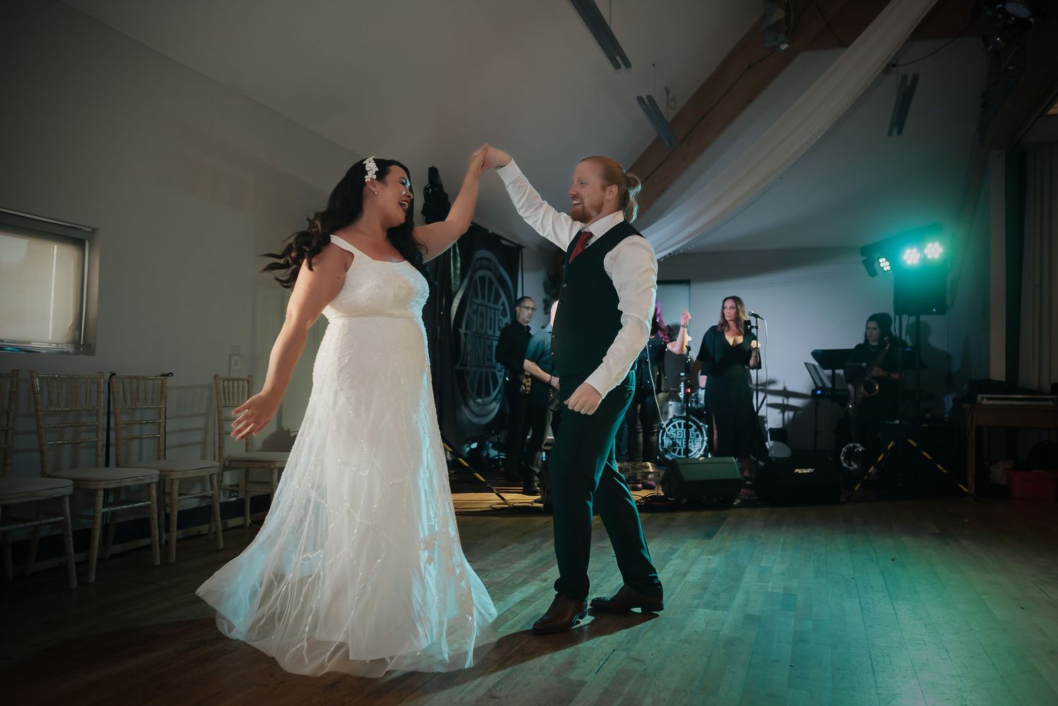 Couple dancing together at wedding reception with band performing in background.