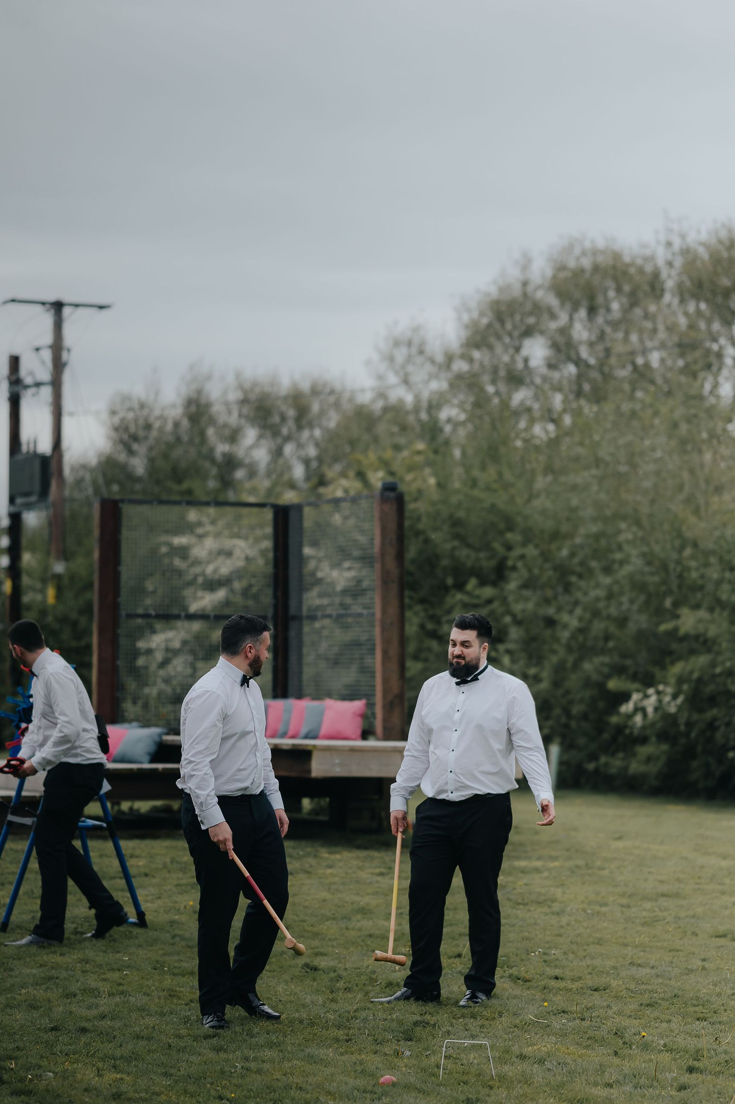 Wedding guests playing lawn games outdoors on a cloudy day.