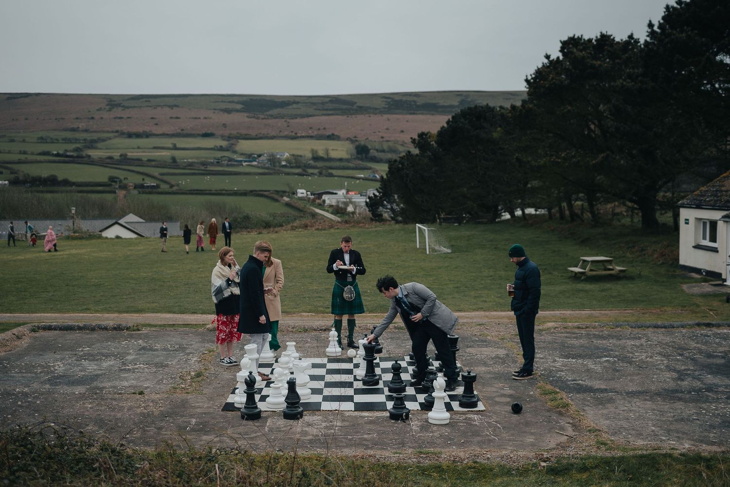 People playing giant chess at outdoor wedding reception.