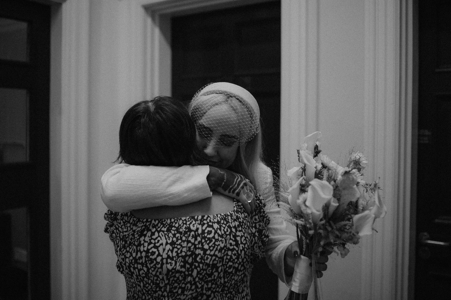 A couple embraces in an intimate dance pose during a wedding reception on a dimly lit dance floor.
