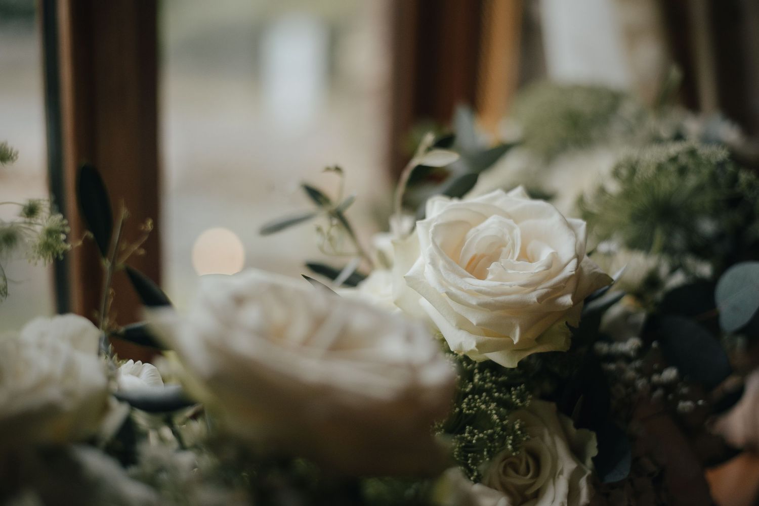 Close-up of white roses and greenery in a wedding flower arrangement.