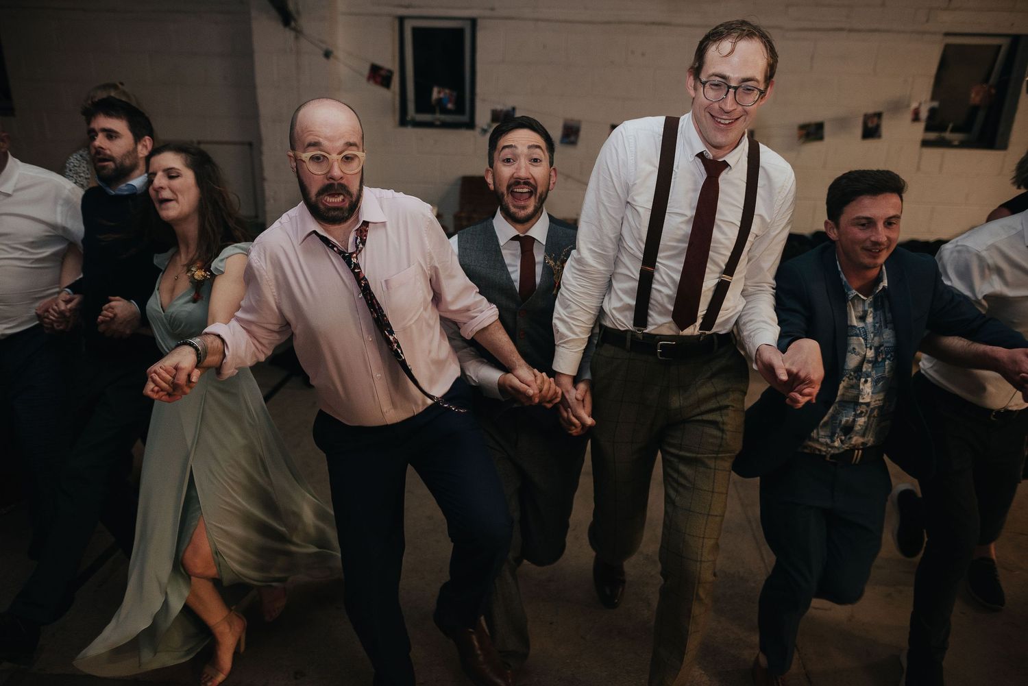 Group of men in formal attire dancing together at a celebration event.