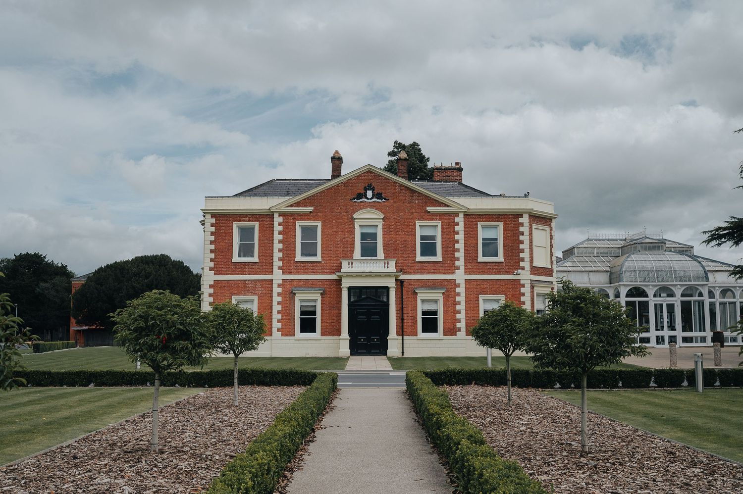 A grand red brick Georgian mansion with symmetrical windows and central entrance.