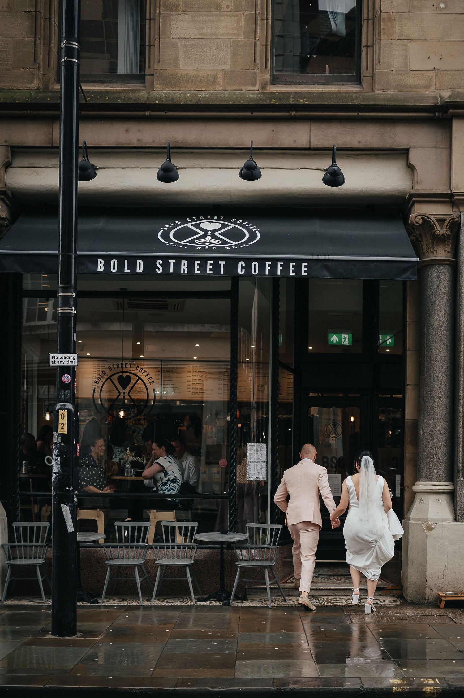 Couple walking towards Bold Street Coffee shop entrance on a rainy day.