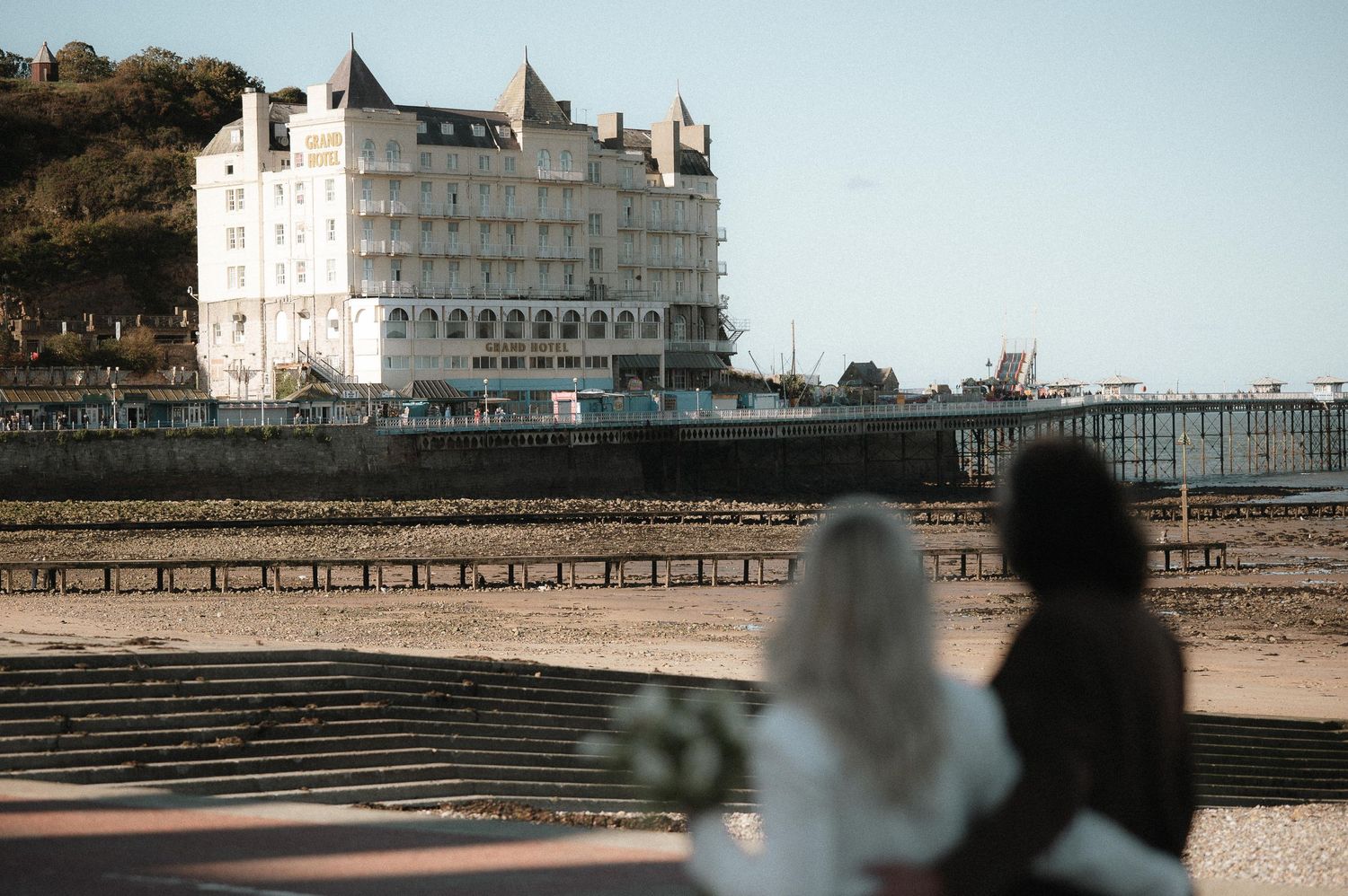Distant view of a grand white seaside building with steps leading up to it.