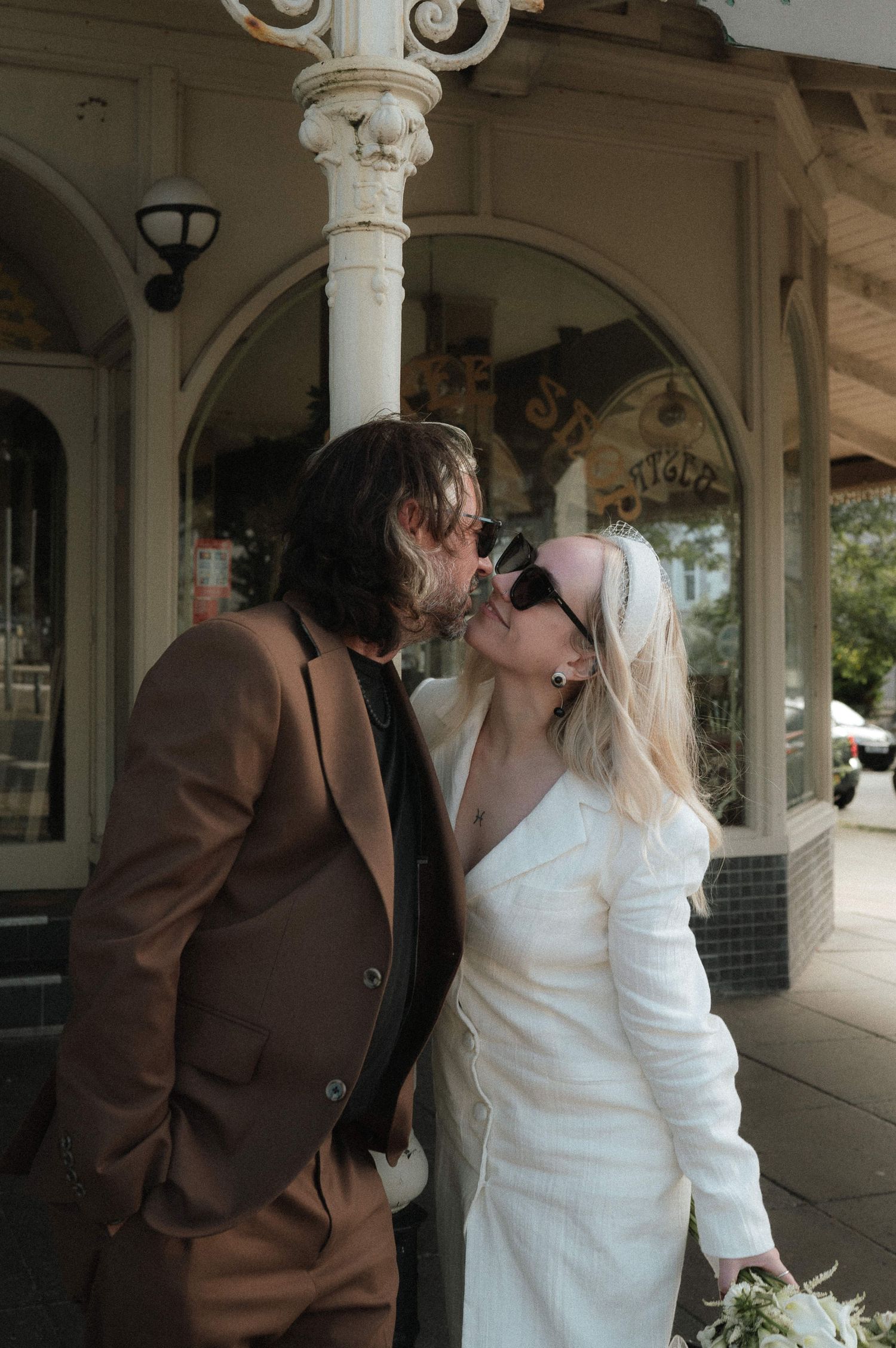 Romantic moment under a decorative white porch with ornate columns.