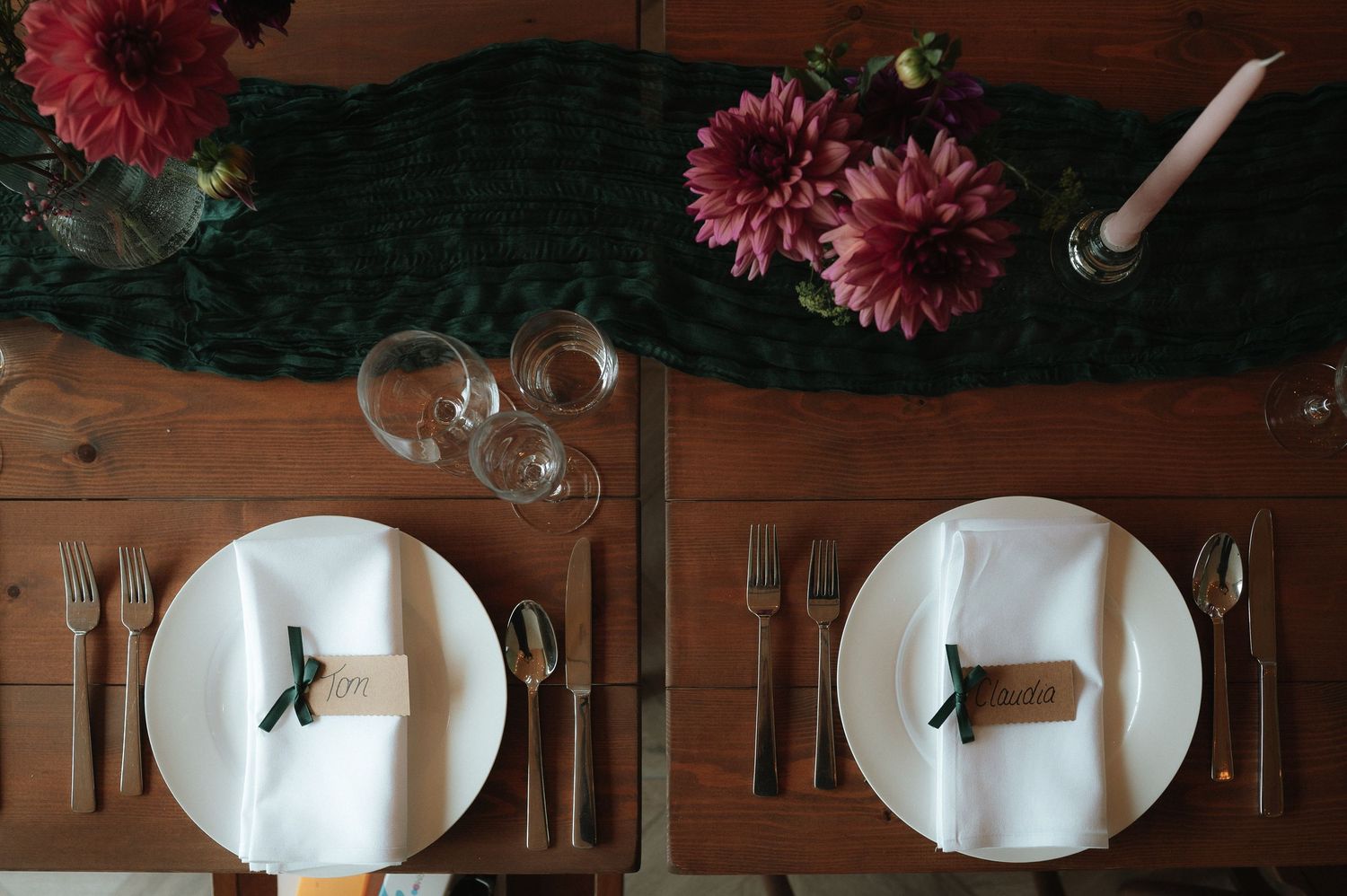 Elegant table settings with dark red dahlias and wine glasses in a rustic dining setup.