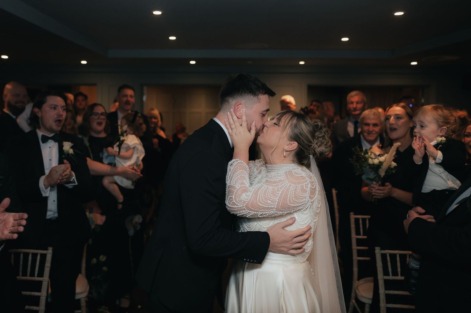 A couple shares a romantic moment during their wedding celebration surrounded by their guests.