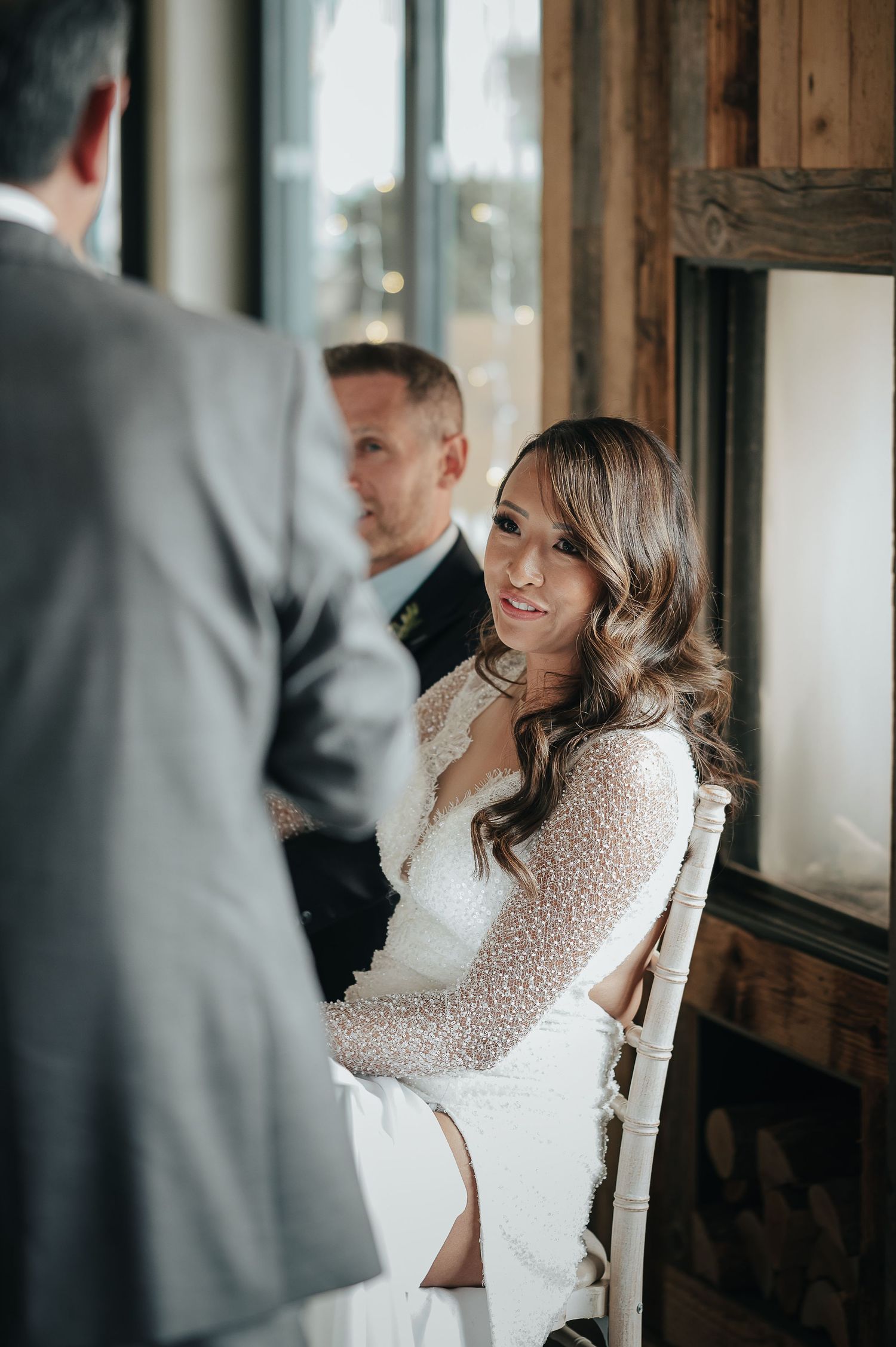 Candid wedding moment featuring a sparkling white lace dress in natural window light.