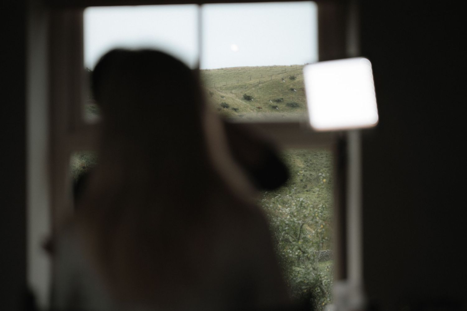 A dark silhouette of a person against a bright window, creating a dramatic contrast in the interior scene.