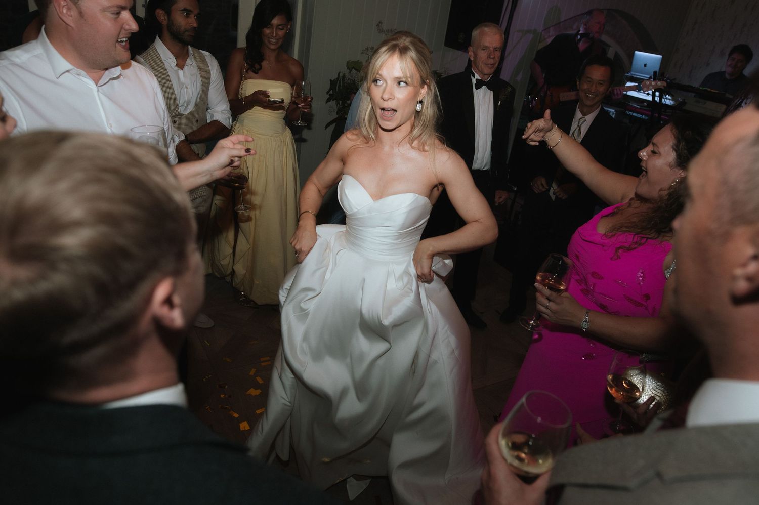 Wedding reception dance party with guests celebrating in formal attire.