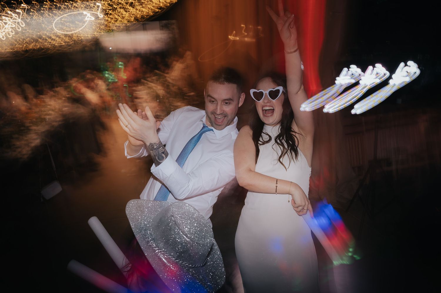 Wedding party guests dancing and celebrating with fun props and motion blur effects.