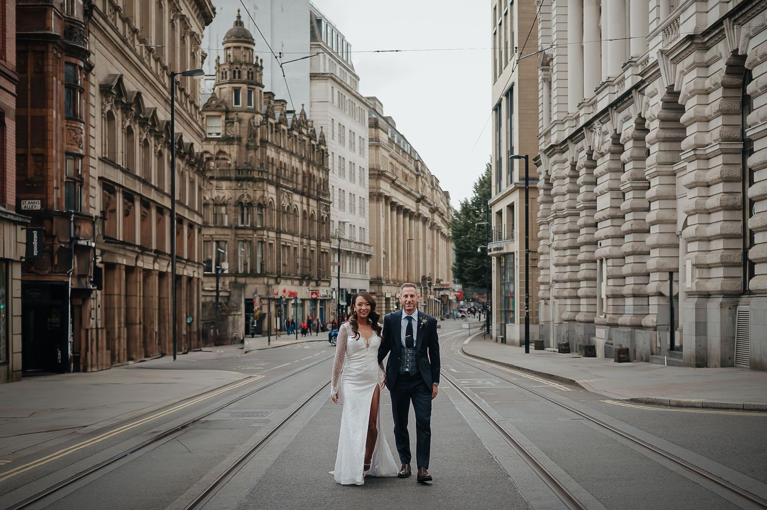 A couple stands together on an elegant city street lined with historic architecture.