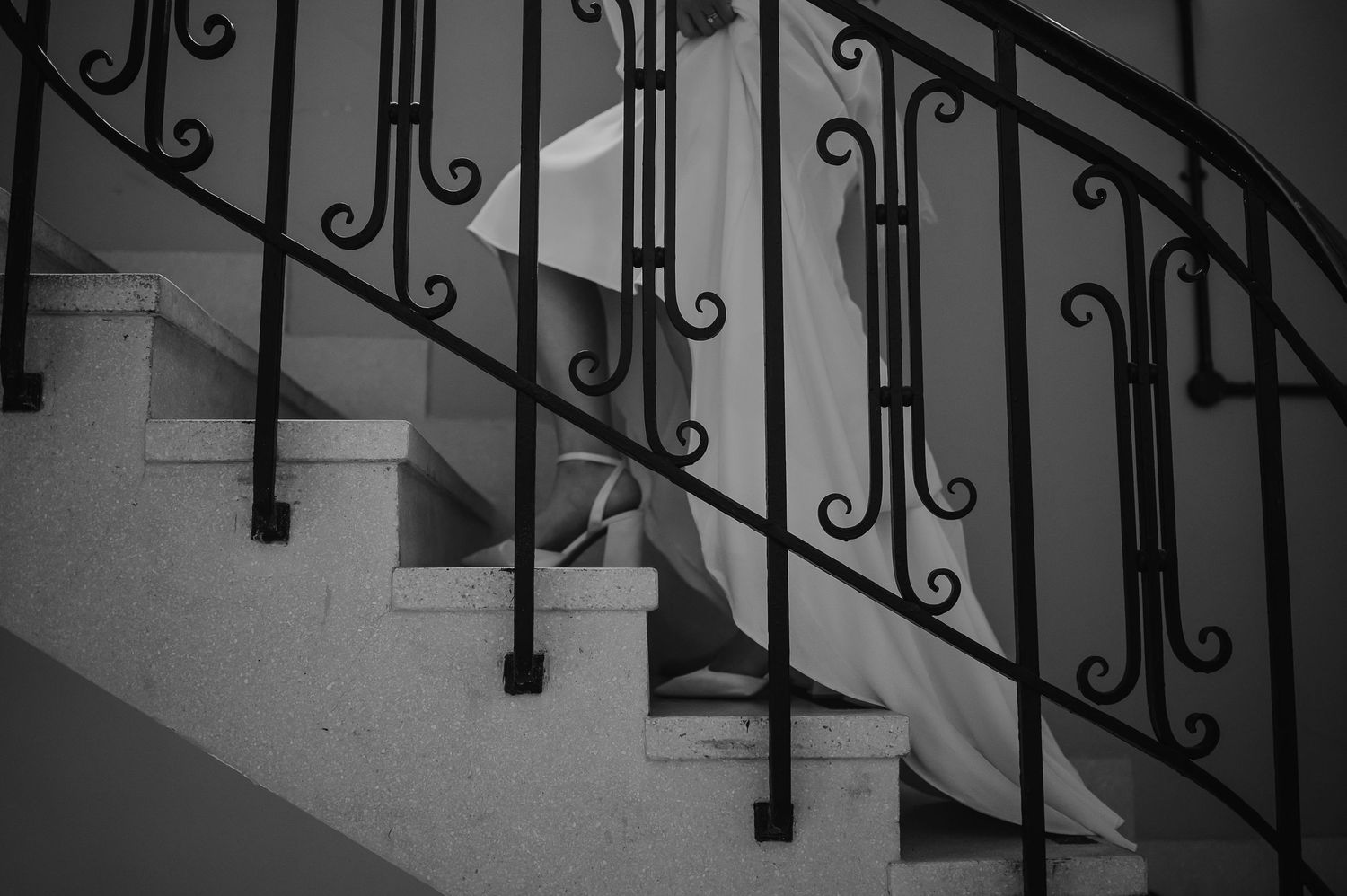 Black wrought iron staircase railing with decorative scrollwork against white wall.