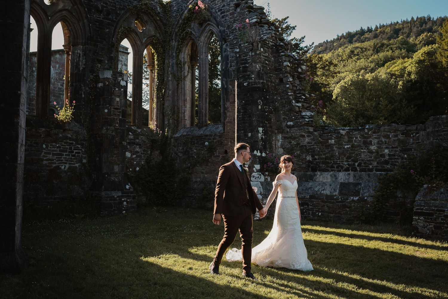 Romantic wedding photo in ancient stone ruins with sunlight streaming through.