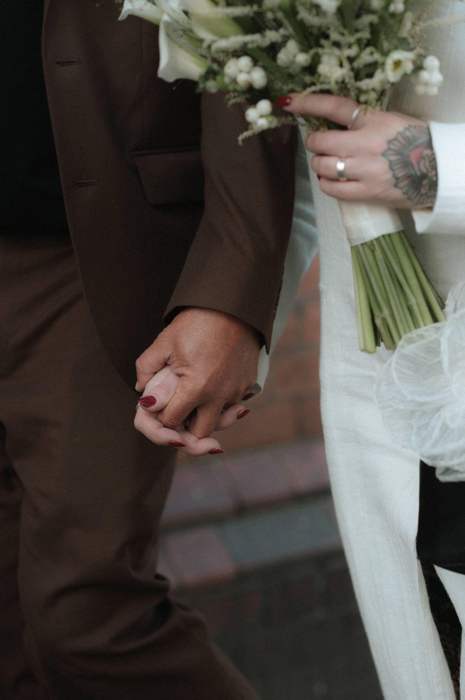 Close-up of hands holding a white floral bouquet with stems wrapped in ribbon.