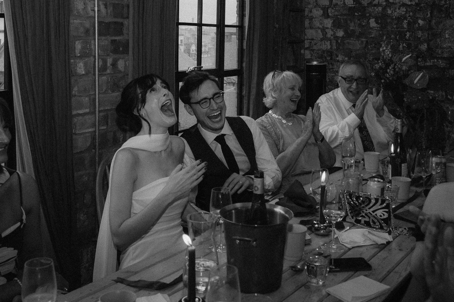 Black and white photo of guests laughing and enjoying themselves at an elegant dinner party celebration.