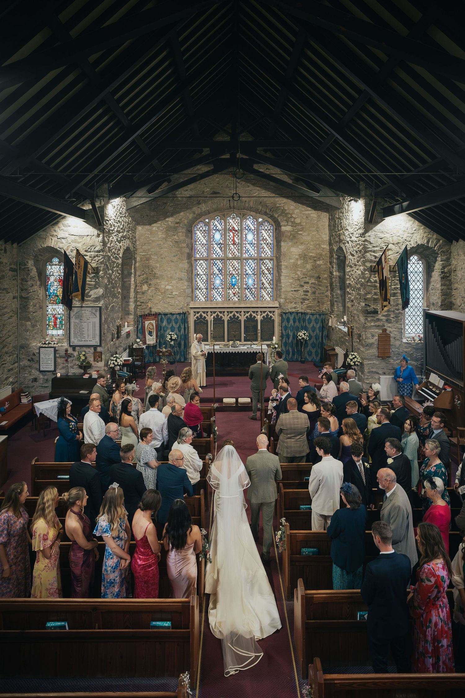 Gothic stone church interior filled with wedding guests during ceremony.
