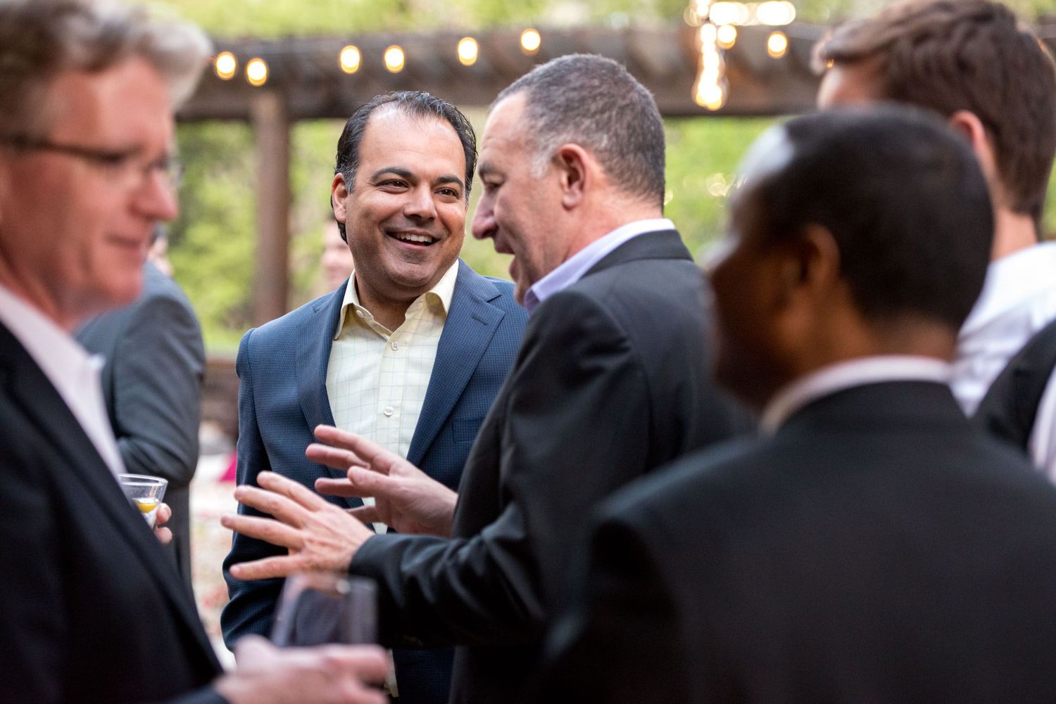Group of professionals networking and engaging in conversation at an outdoor business event.