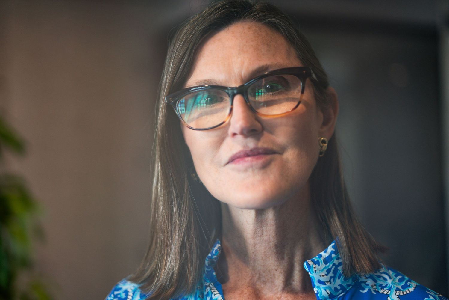 Professional wearing glasses and a blue shirt in an office setting.