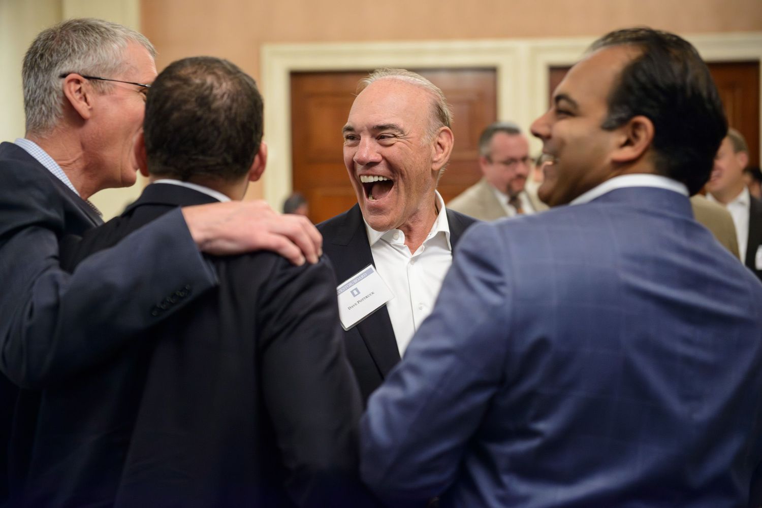 A group of business professionals share a lighthearted moment during a networking event.