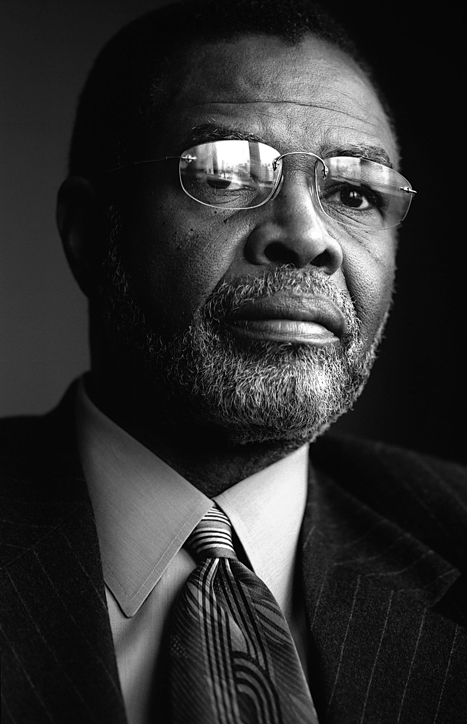 Dramatic black and white portrait series showing different angles of a person in glasses and pinstripe suit.