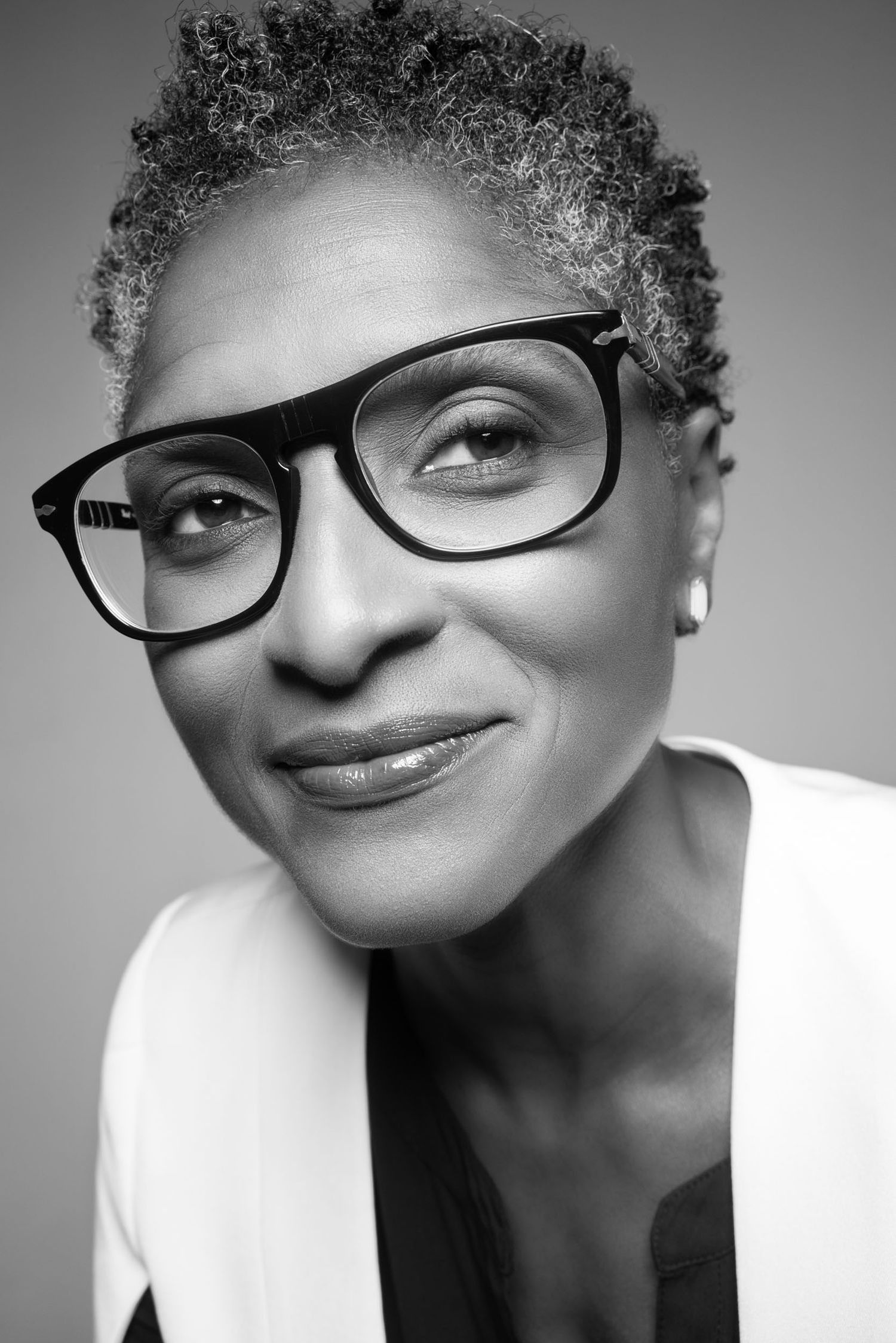 Black and white portrait of person wearing glasses against neutral background.