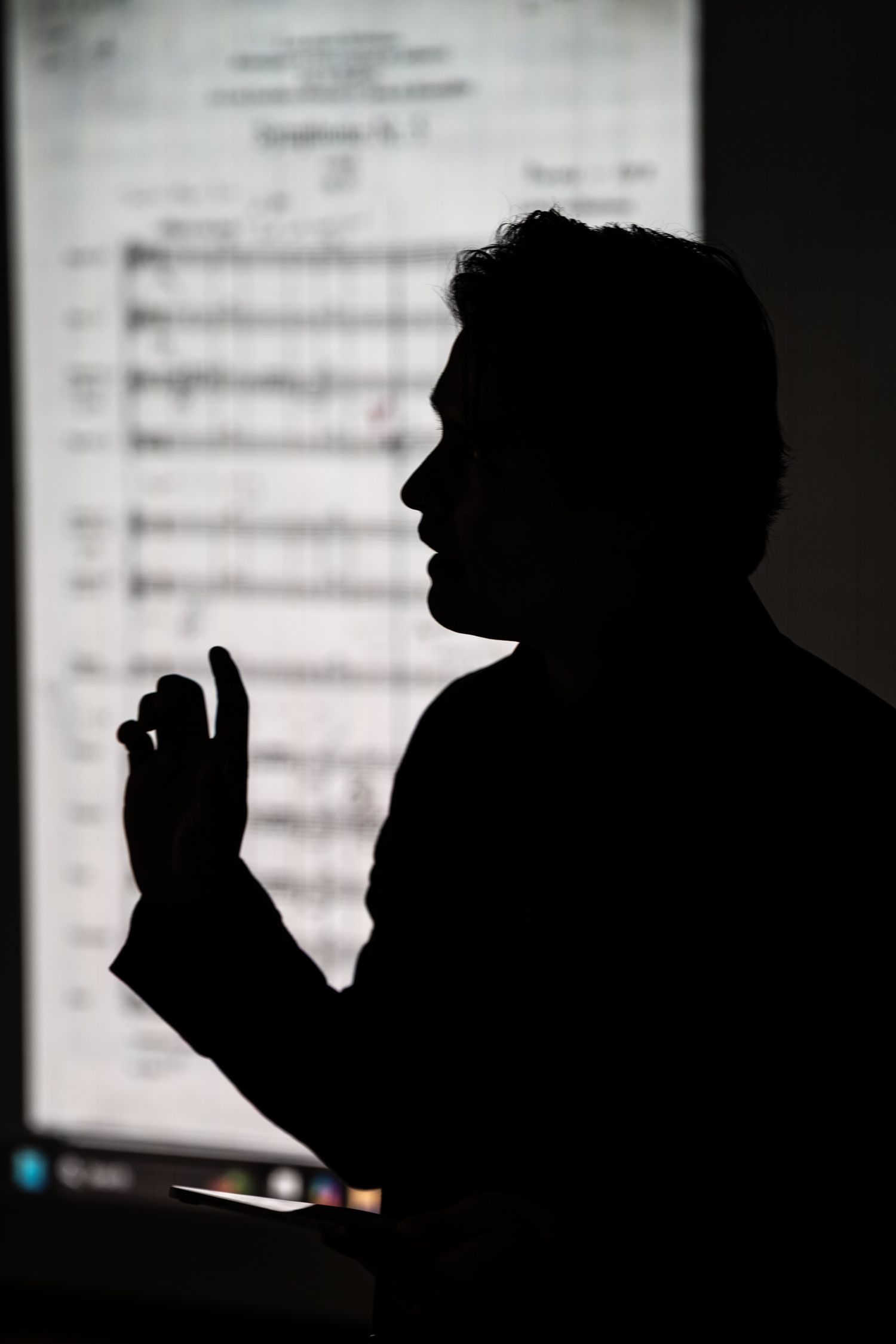 A silhouetted figure appears in a dark profile against a blurred light background with text.