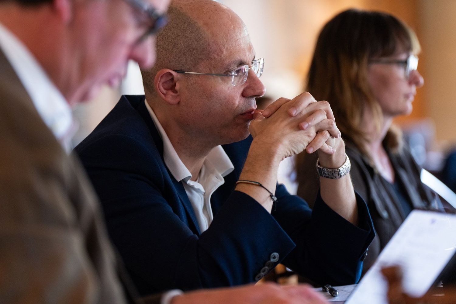 Business professionals seated in a row at a conference or meeting listening attentively to a presentation.