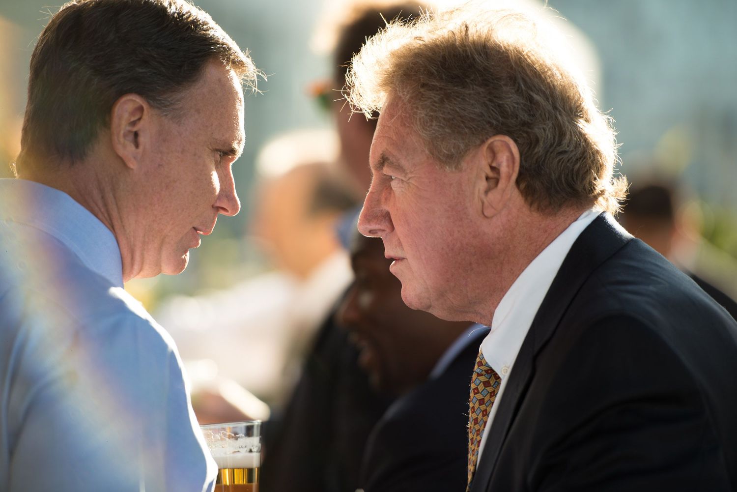 A sequence of three candid photos showing people in suits engaged in conversation at a formal event.