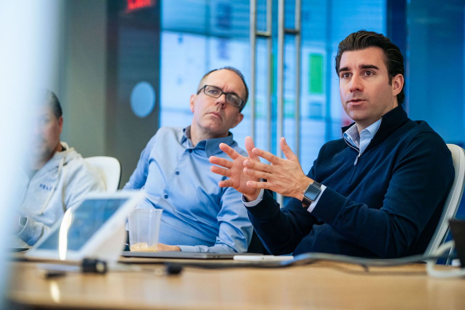 Business professionals seated at conference table during corporate meeting in modern office setting.