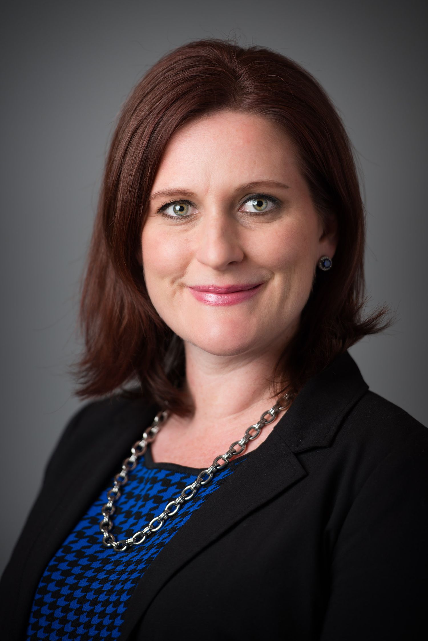 Professional headshot series showing different angles and expressions of a person in a black blazer and blue patterned top.