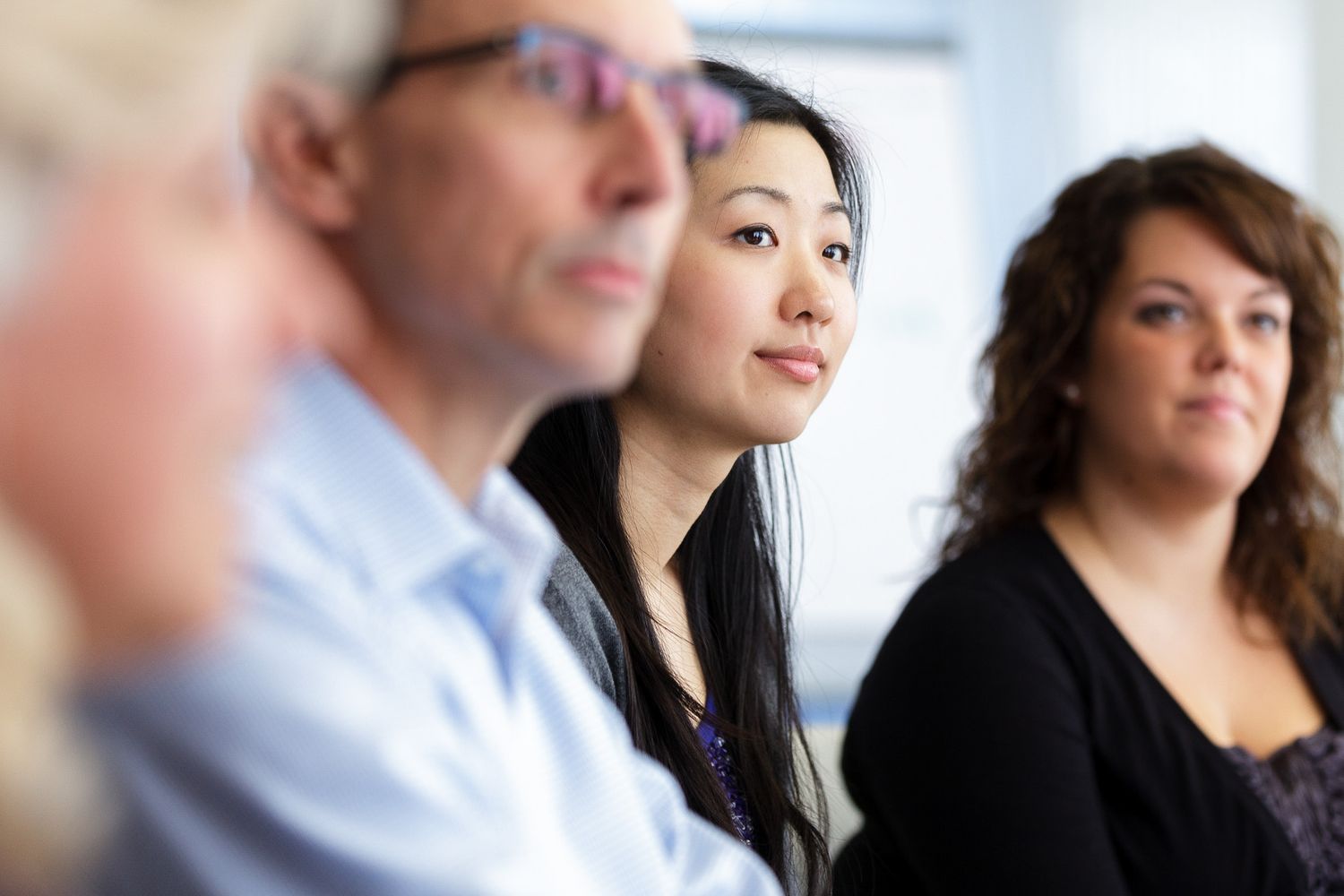 Team members seated at a conference table engage in discussion during an office meeting.