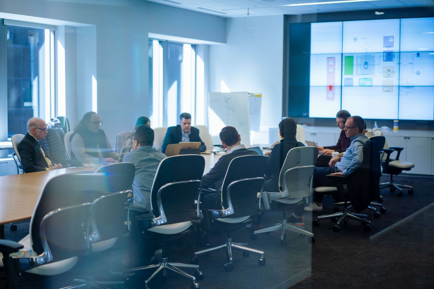 Modern office conference room with glass windows and multiple seating areas.