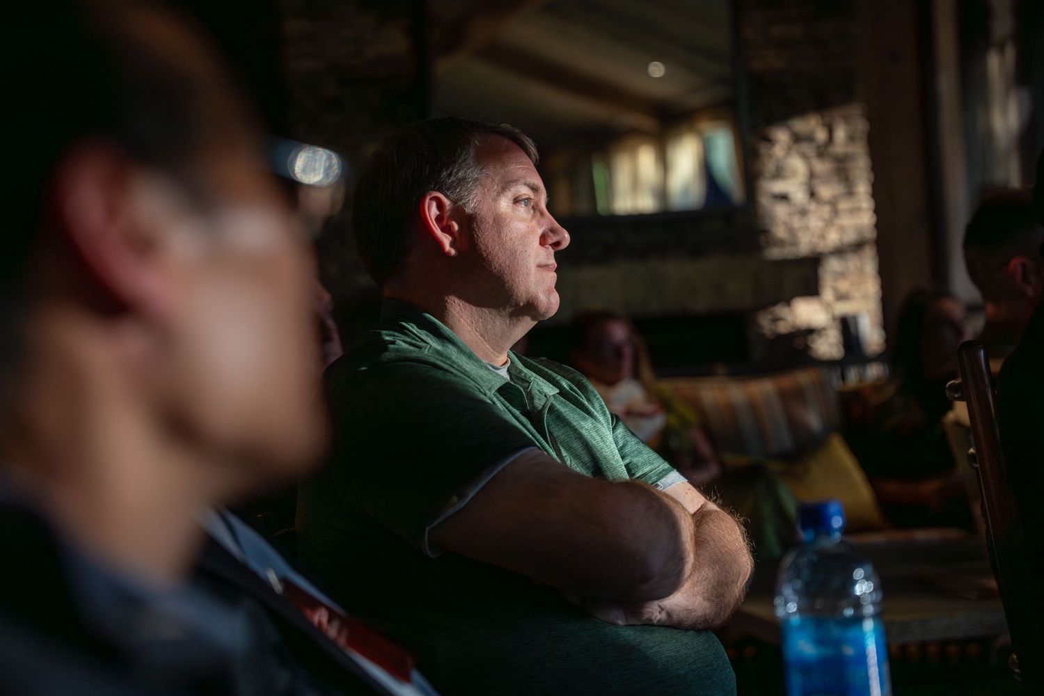 A person watching intently in a dimly lit room with a blue water bottle visible in the frame.