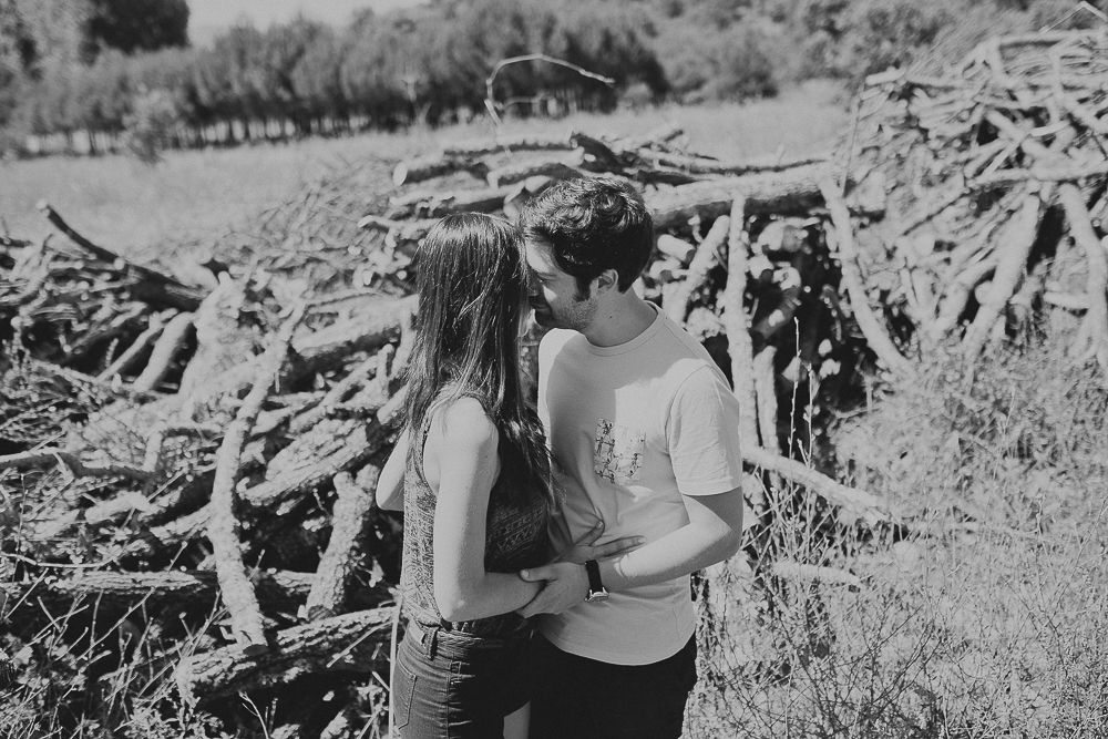 Intimate black and white portrait of couple by natural wood pile.