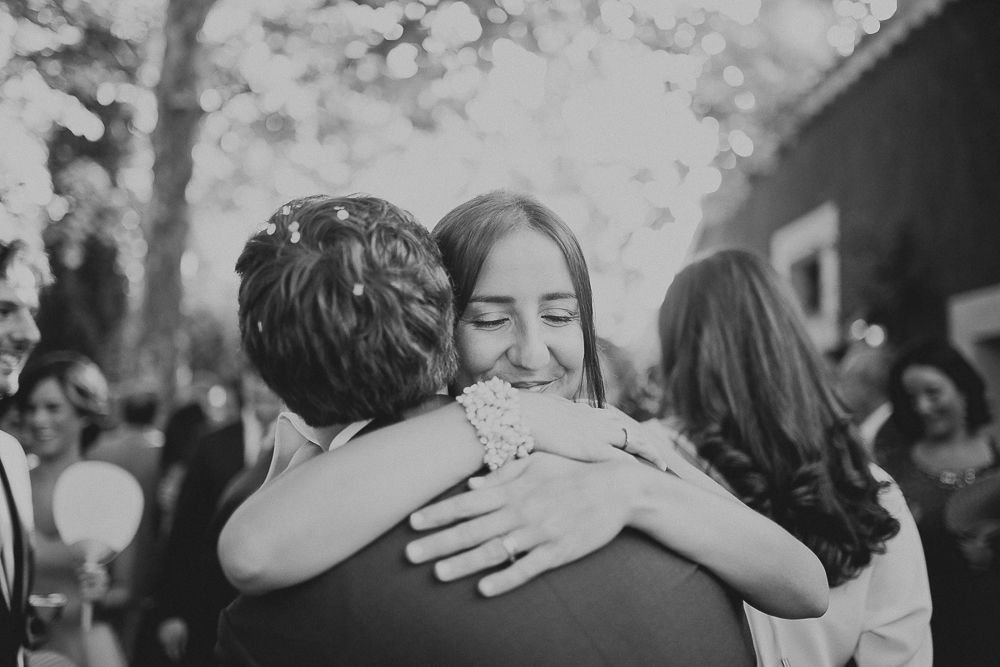 An emotional embrace captured in black and white at an outdoor celebration.