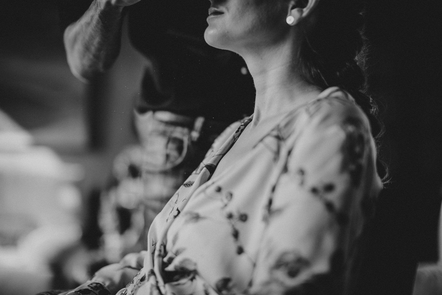 Soft black and white portrait showing elegant floral dress details in ambient lighting.