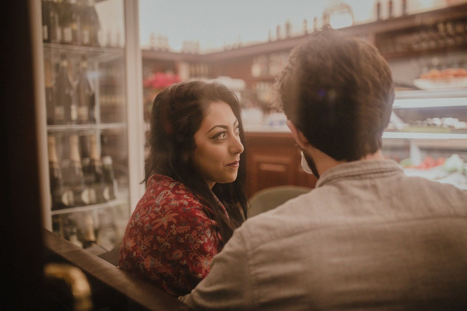 A couple sharing an intimate moment in front of a restaurant window at sunset.
