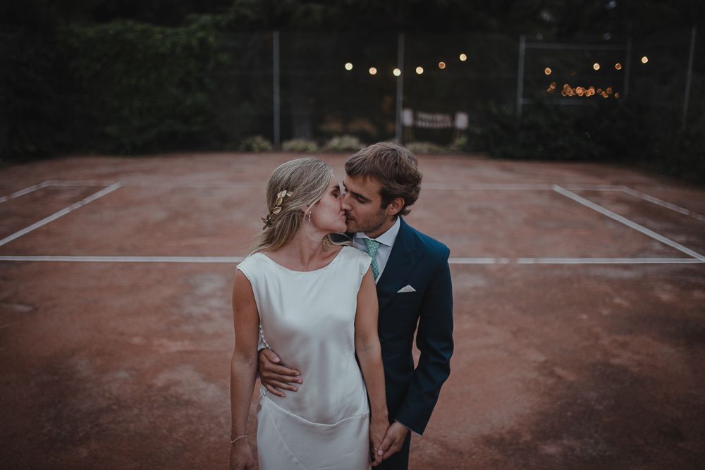 Intimate couple portrait at dusk on a tennis court with moody lighting.