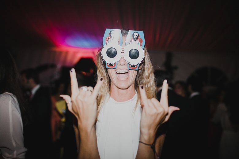 Person wearing a fun LED light-up mask making rock gestures at a party.