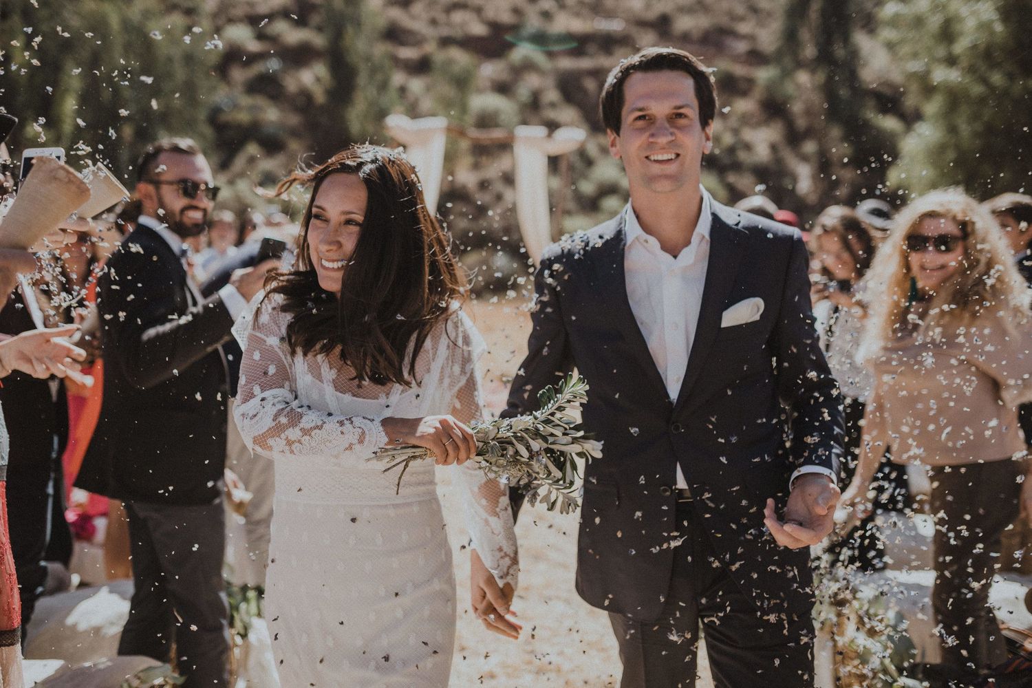 Wedding guests shower the happy couple with confetti as they walk down the aisle together.