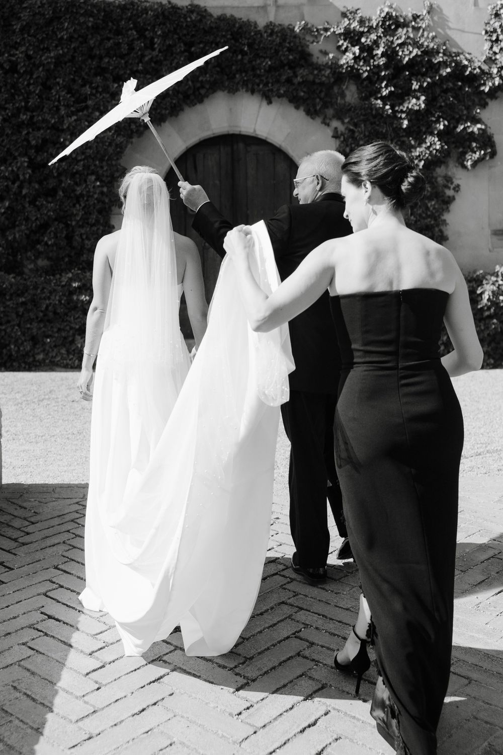 Black and white wedding photos showing the back of formal attire on a brick pathway.