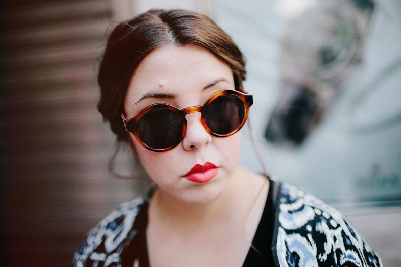 Stylish round sunglasses and red lipstick create a vintage-inspired portrait.