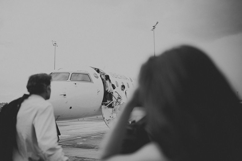 View of an aircraft nose through an airport window in black and white.